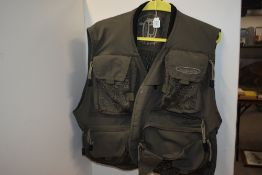 A set of olive green salopets and a vision fly fishing waistcoat hanging from a set of hardy wader