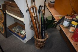 A selection of walking sticks in a small wicker basket along with a copper post horn and a carpet