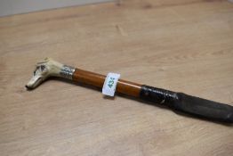 A small hunting crop with with white metal ferrule and a carved bone dogs head whistle