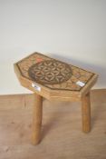 A vintage wooden milking stool, upon three turned legs, having a pyrographic geometric pattern atop,