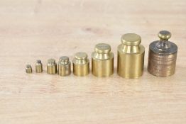A set of eight 20th-century brass apothecary weights, with plastic storage box, (8), condition is