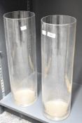 Two tall contemporary studio glass vases, off a slender cylindrical form, pontil mark to base,