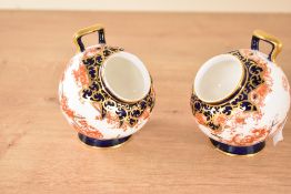 A pair of Royal Crown Derby 'Imari' pattern condiment pots of circular form raised on a footed base,