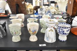 A quantity of late 19th to 20th-century ceramic double egg cups, to feature various handpainted