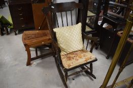 A traditional dark stained rocking chair , having turned frame