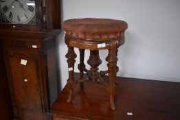 A Victorian mahogany circular piano stool with four turned and incised legs linked by stretchers and