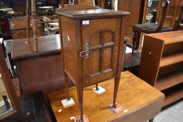 An arts & Crafts oak pot cupboard, with shallow arched back over the moulded square top with
