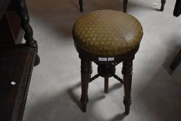 A 19th century mahogany revolving piano stool, the circular padded seat with revolving action over