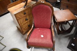 A Victorian oak rocking chair, having a lobed crest rail over padded and upholstered back, the