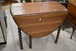 An early 20th century barley twist oak gate legged table, of traditional design with oval flaps, and