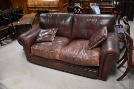 A modern chestnut brown stained leather two seater settee with two cushions, 80cm x 160cm x 100cm