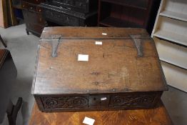 An 18th century oak bible box, of typical sloped and hinged front design with original iron strap