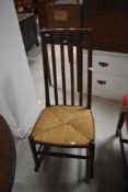 A small attractive Arts & Crafts style string seated rocking chair, having a shaped top rail,