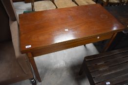 An Edwardian mahogany fold-over tea table, of hinged rectangular form with in laid rail and tapering