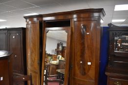An early 20th century figured mahogany triple wardrobe, having a dentil moulded cornice and plain