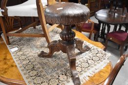 A Victorian revolving piano stool, the circular padded seat with revolving action over a fluted