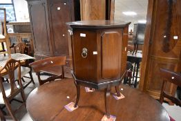 An reproduction mahogany octagonal drinks cabinet with inset leather surface to top and piano hinged