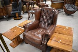 A modern brown leather wing-back armchair, with deep buttoned back and studded edge detail, seat