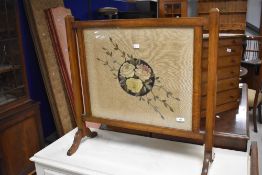 An Edwardian oak needlework fire screen, of traditional design with foliate needlework panel 69cm