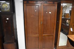 A reproduction mahogany double door wardrobe, having a dentil moulded cornice and plain frieze