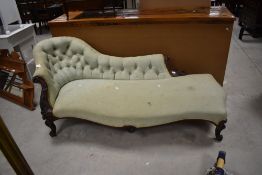 A Victorian mahogany framed chaise longue, having a shaped and deep buttoned back with foliate