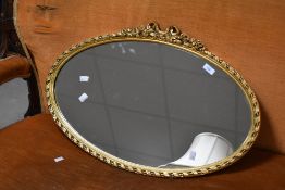 A 1970's 19th century design oval gilt framed mirror with knotted ribbon crest and twisted ribbon
