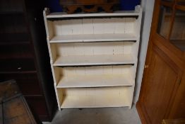 A late painted Victorian waterfall bookcase, having five graduating tiers between shaped uprights,