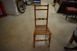 An Edwardian cane seated bedroom chair, with decorative pierced base rail and turned front