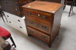 An Edwardian banded mahogany chest of three cockbeaded drawers, each with embossed brass back plates