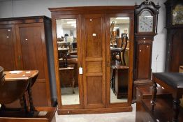 An early 20th century mahogany triple wardrobe, having a moulded cornice and plain frieze over the