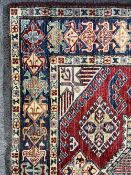 A vintage Afghan Kazak rug in red, blue and neutral wool, featuring a star shaped central