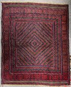 A Persian area rug in red wool with navy and brown accents, having a central diamond tiled design,