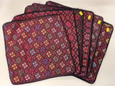 Six vintage hand cross-stitched cushion covers, with mostly red threads on a black ground, having