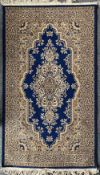 A small area rug in blue and gold fine ornate design, having a central medallion and fringed edging,