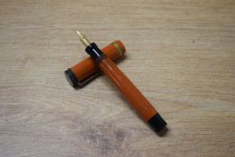 A National Security button fill fountain pen in Coral with broad cap band to flat top cap having