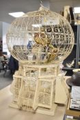 A 19th century white painted metal decorative bird cage featuring ornate wirework design and