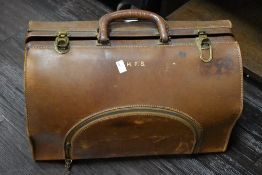 A large early 20th-century tan leather Gladstone bag, featuring brass-toned hardware and clasps,