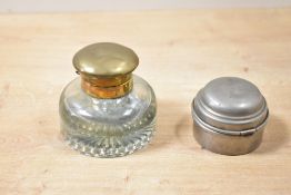 An early 20th-century glass ink well having a brass lid, with a star cut pattern to base; sold