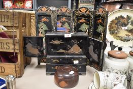 An Oriental black lacquer table cabinet featuring decorative bird and floral motifs, metal bound