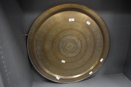 A large mid to late 20th-century Eastern brass charger, having engraved floral and scrollwork motifs