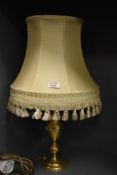 A 20th-century classic-style table lamp, having a brass-toned base and cream-coloured fabric shade