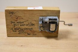 A contemporary handmade, palm size wooden music box, featuring a visible hand crank mechanism that