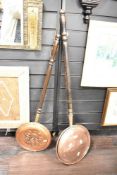 Two late 19th to early 20th-century copper and brass bed warming pans, featuring turned wood