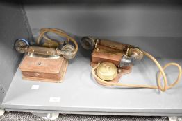 Two late 19th to early 20th-century bell wall telephones, featuring wooden bases, metal phones and