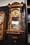 A 19th-century Vienna-style wall clock, featuring a carved wooden case, ornately turned columns