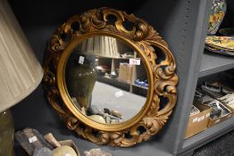 A vintage ornate gilt resin oval wall mirror, featuring a carved, scrollwork frame, unmarked,