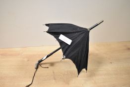 A 19th-century miniature fabric doll's parasol, featuring a black canopy, wooden shaft and white