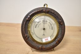 A late 19th-century English aneroid barometer in a carved wooden case, featuring an ornate, rope