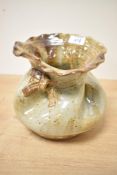 A 20th century studio pottery stoneware vase, formed as a loosely tied sack with mottled buff glaze,