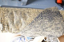 A large bolt of woven wool blend jacquard fabric in camel colour with black snakeskin print